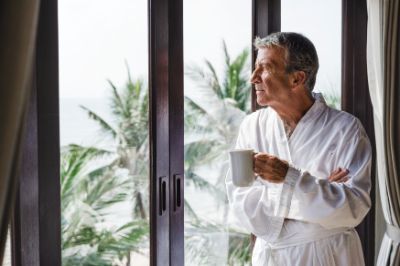 mature-man-looking-out-hotel-window